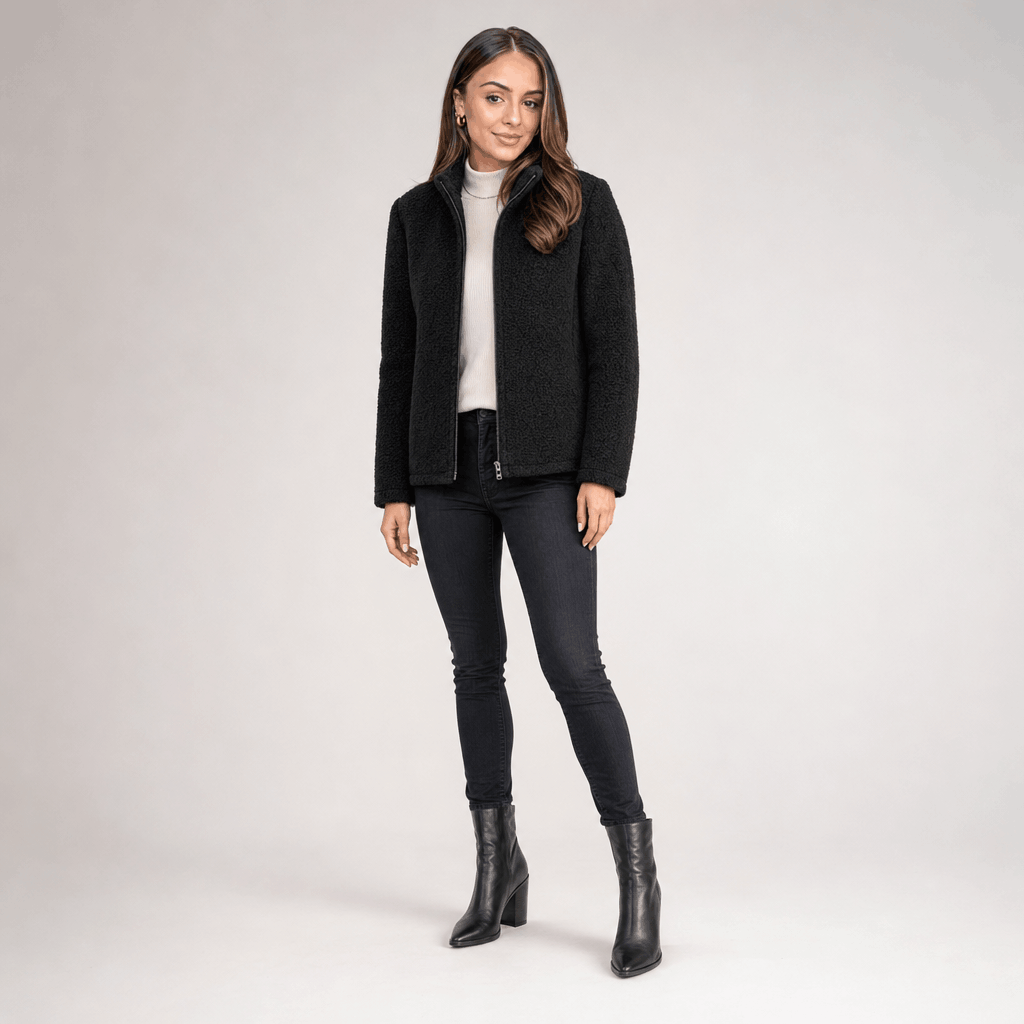 Full-body view of a female model wearing the black jacket with dark trousers and black ankle boots.
