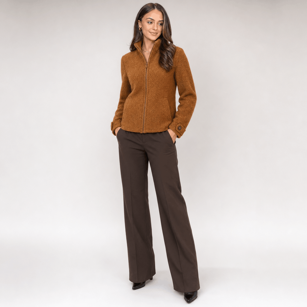 Full-body view of a female model wearing the camel brown jacket with dark trousers.