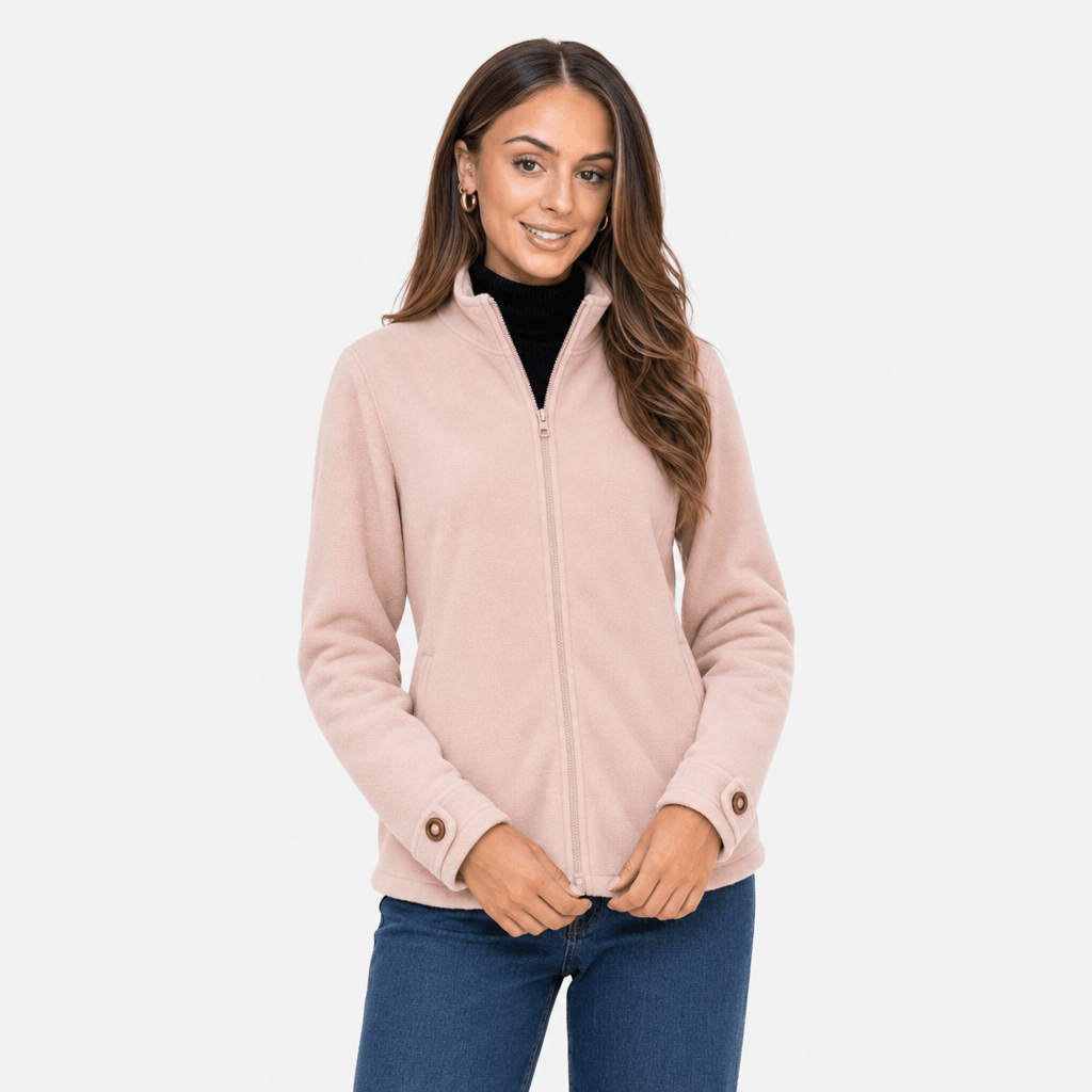 Female model wearing a light blush pink zip-up jacket with blue jeans.