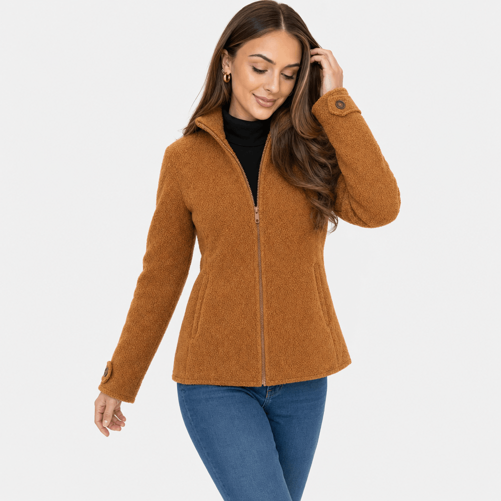 Female model wearing a camel brown zip-up jacket with a stand collar, paired with a black top and blue jeans.