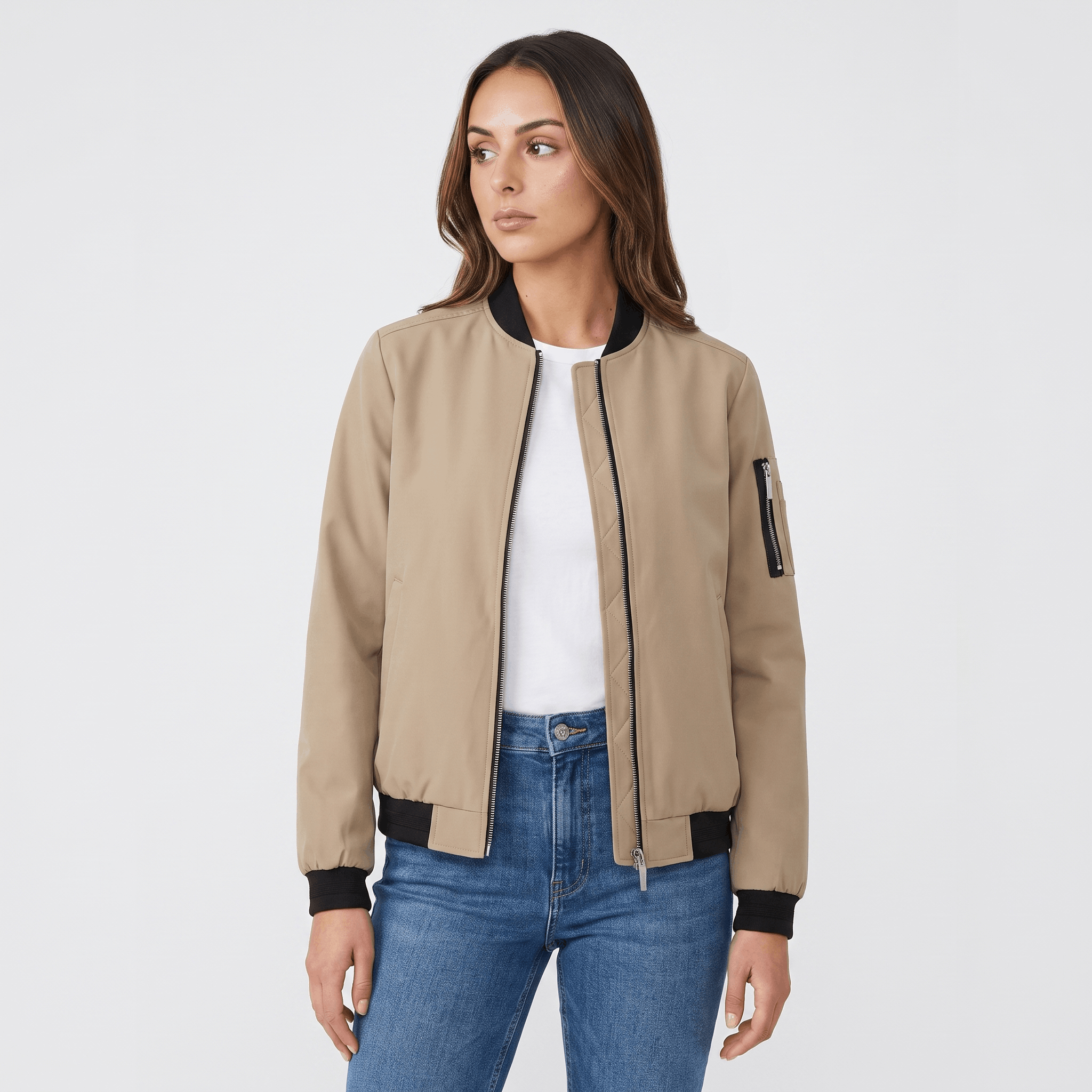 Female model wearing a beige bomber jacket over a white top with blue jeans.
