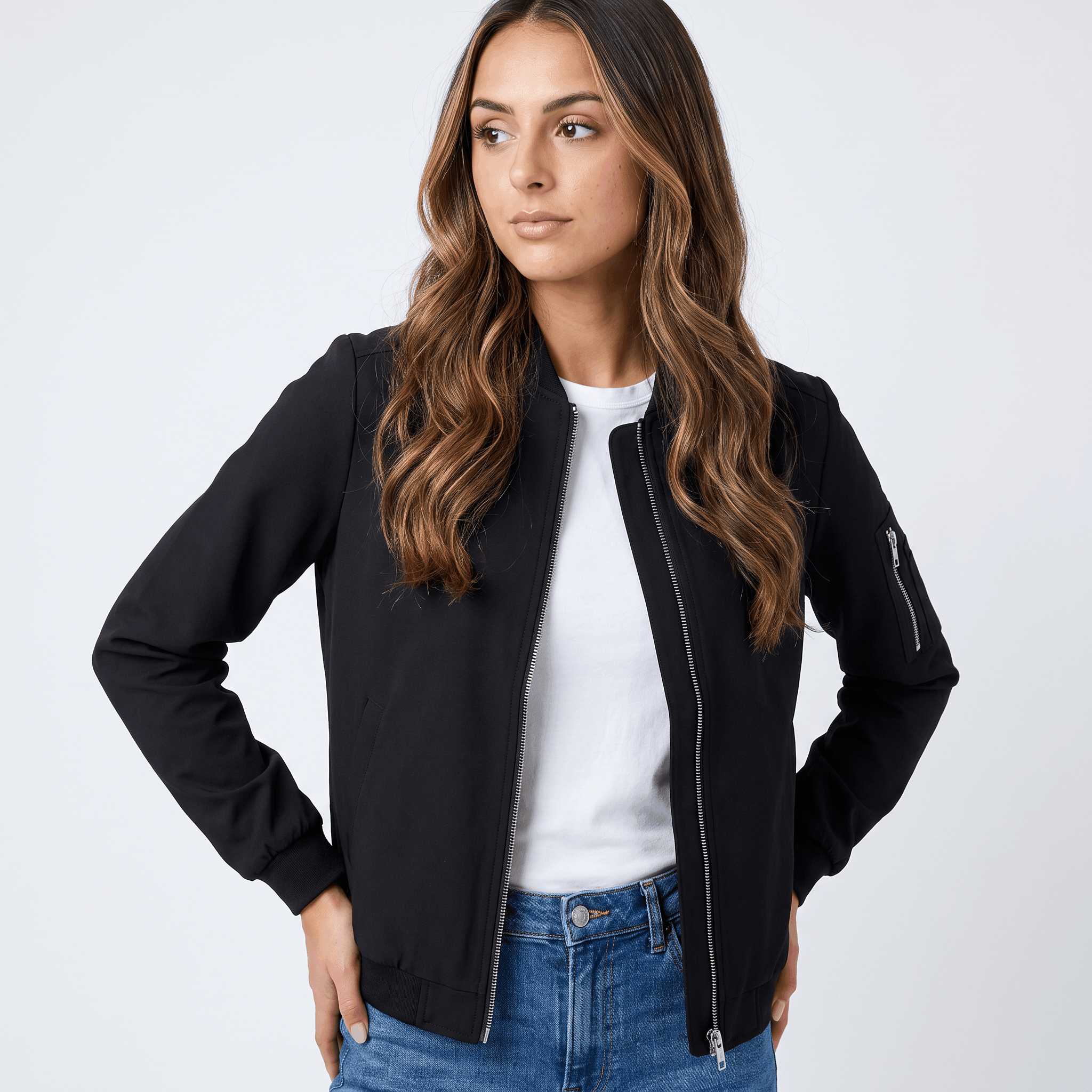 Female model wearing a black bomber jacket over a white top with blue jeans.