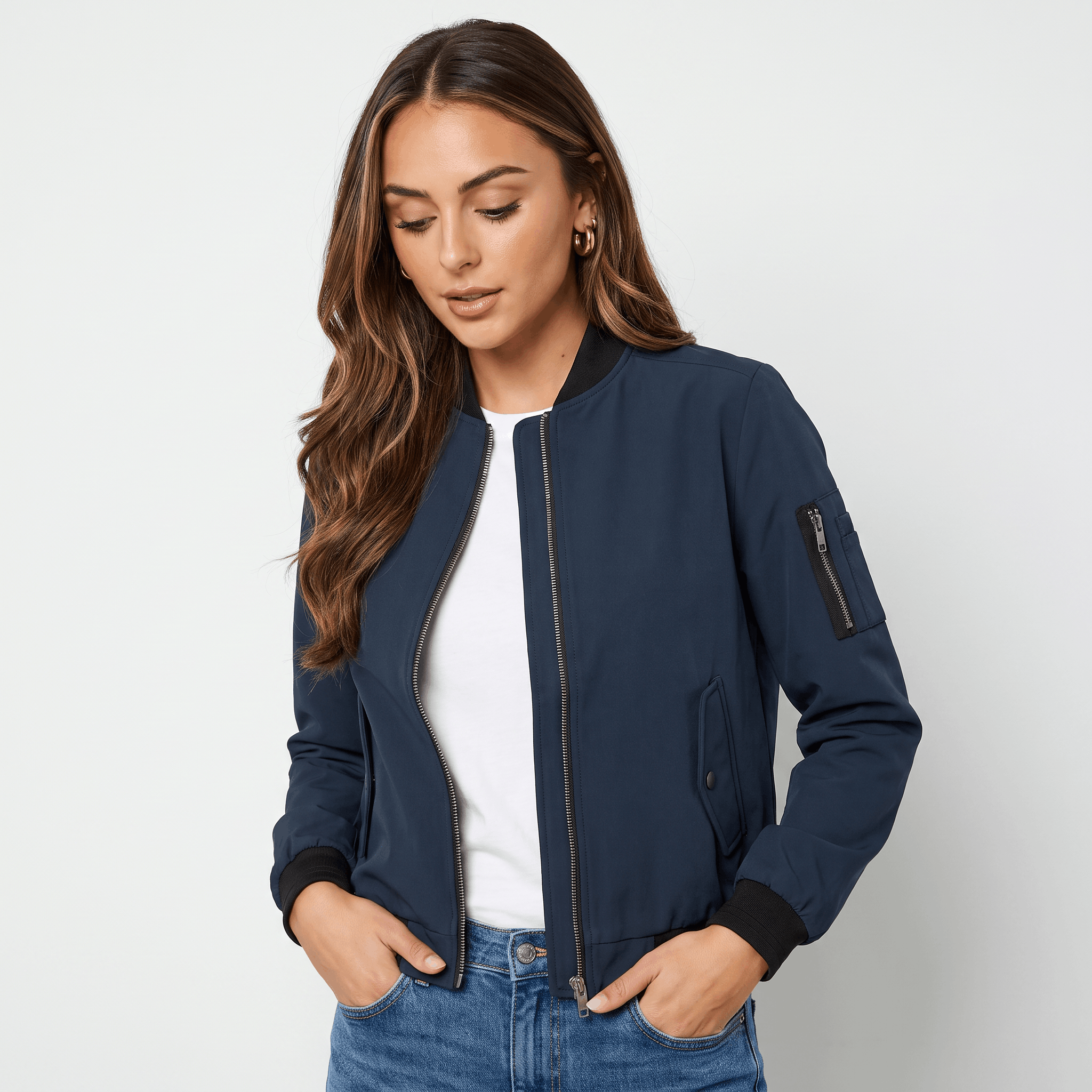 Female model wearing a navy blue bomber jacket over a white top with blue jeans.