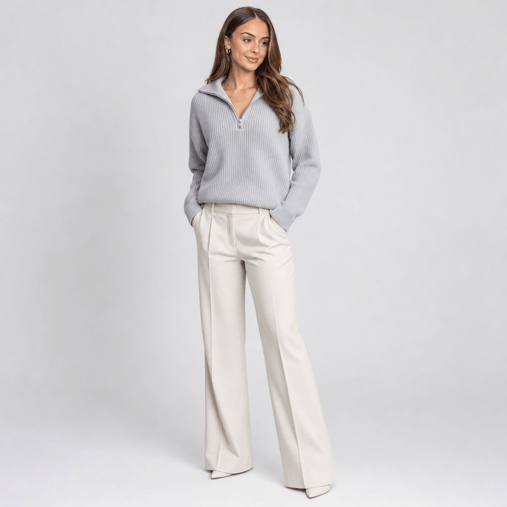 Full-body view of the woman wearing the light gray ribbed half-zip sweater with white wide-leg pants.