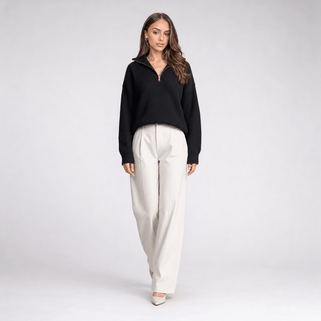 Full-body view of the woman wearing the black ribbed half-zip sweater with white wide-leg pants.