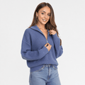 Woman wearing a slate blue ribbed half-zip sweater with blue jeans, shown in a relaxed front-facing pose.