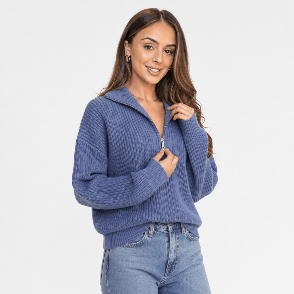 Woman wearing a slate blue ribbed half-zip sweater with blue jeans, shown in a relaxed front-facing pose.