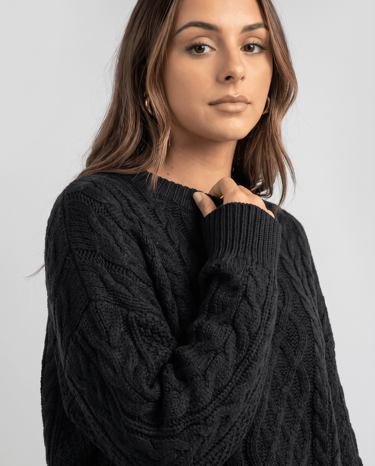 Black Cable Knit Sweater worn by a female model, featuring an oversized fit, textured cable knit pattern, long balloon sleeves, and a relaxed silhouette.