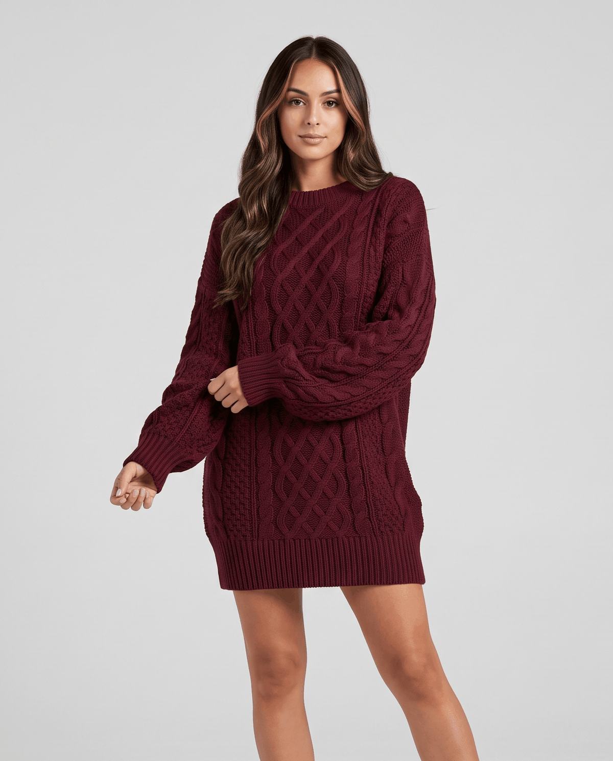Burgundy Cable Knit Sweater worn by a female model with a short skirt and tall boots, featuring an oversized fit, textured cable knit pattern, and balloon sleeves.