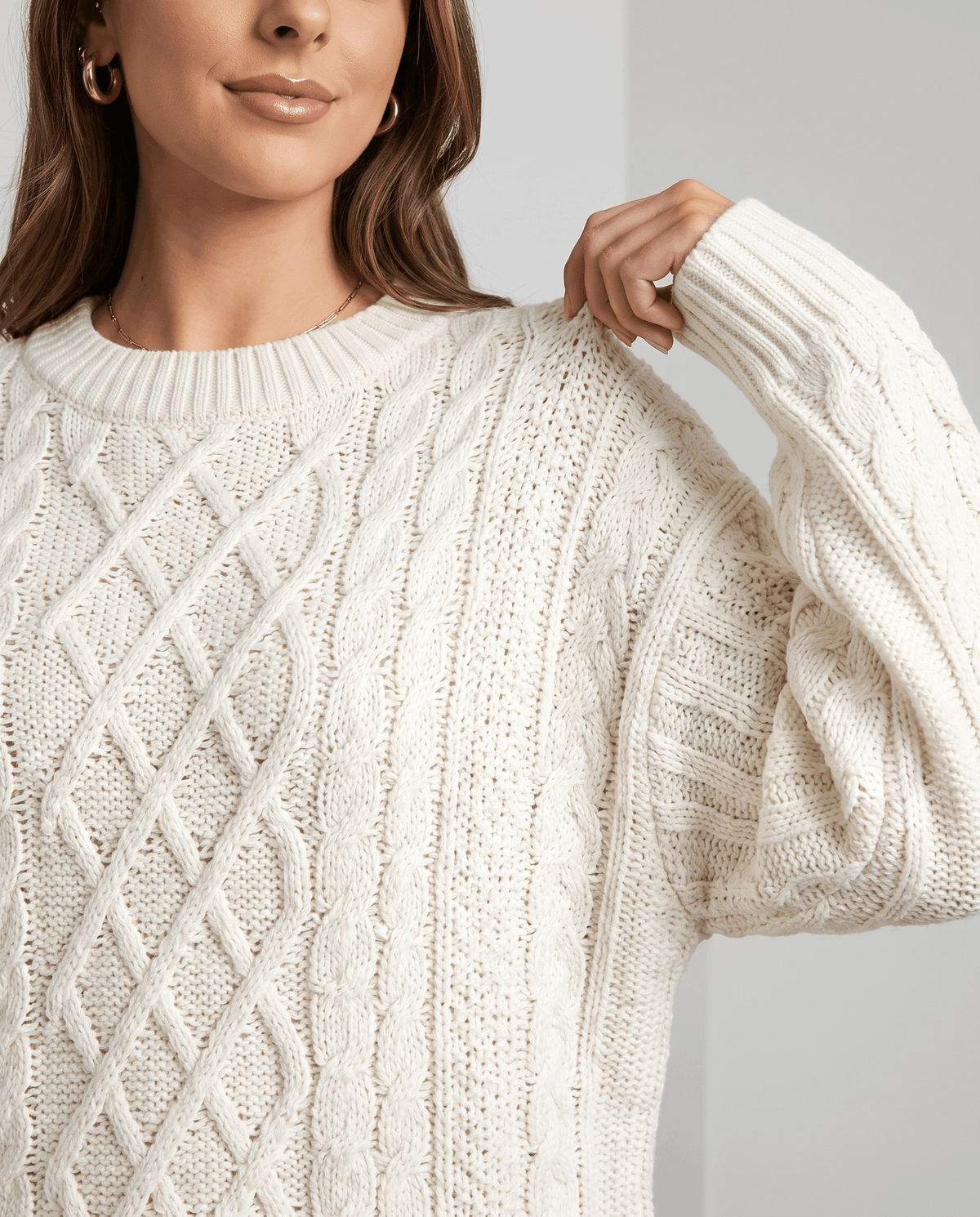 Cream Cable Knit Sweater worn by a female model, shown in close-up to highlight the textured cable knit pattern, oversized fit, and balloon sleeve.
