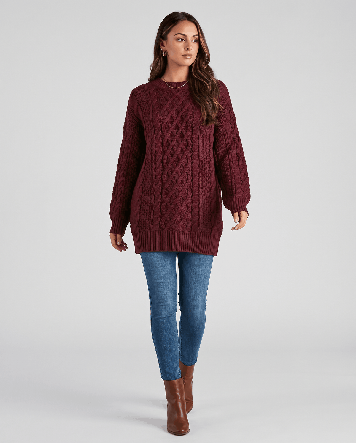 Burgundy Cable Knit Sweater worn by a female model with blue jeans and boots, featuring an oversized fit, textured cable knit pattern, and long balloon sleeves.