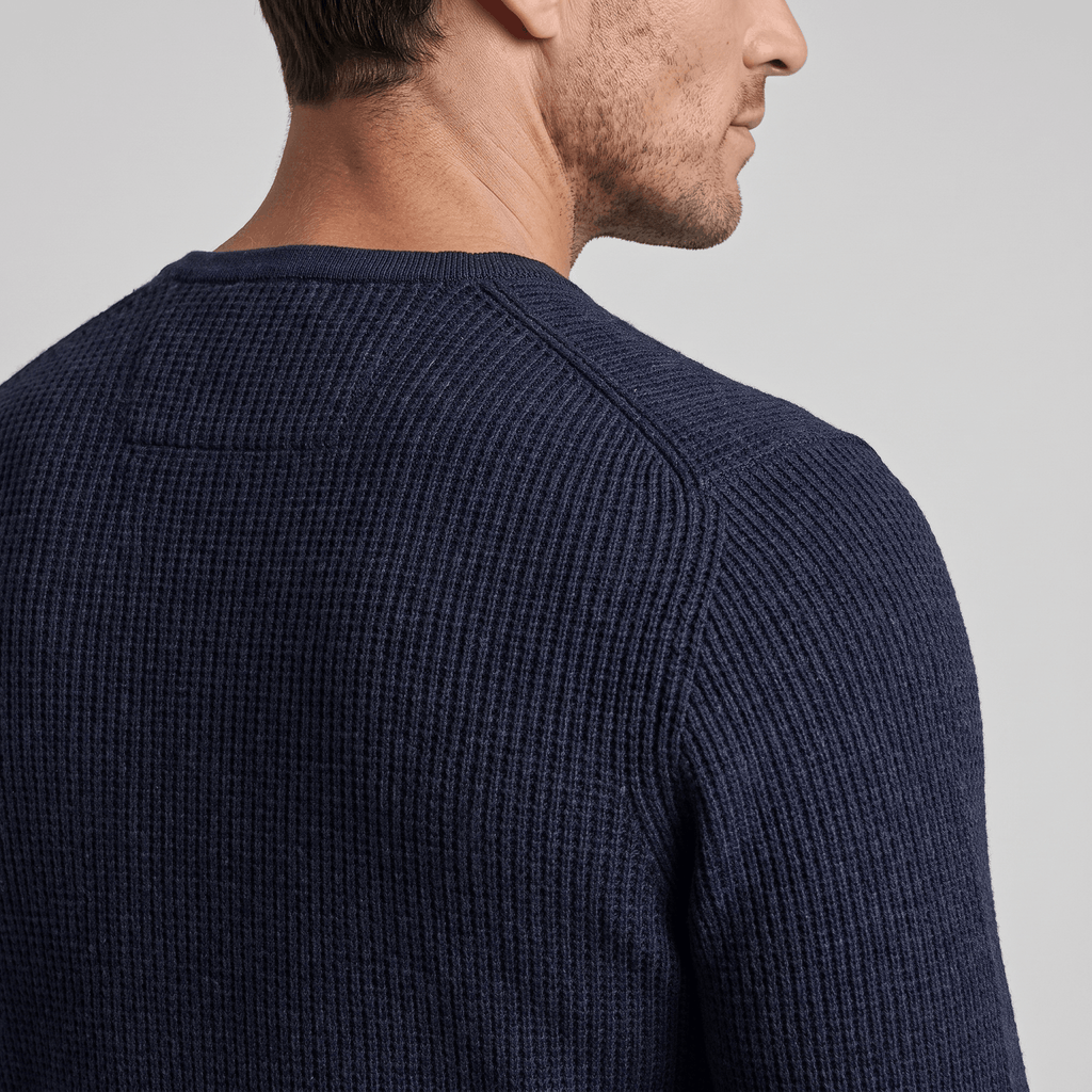 Navy blue ribbed knit henley sweater with a regular fit and structured shoulder detail on a man.