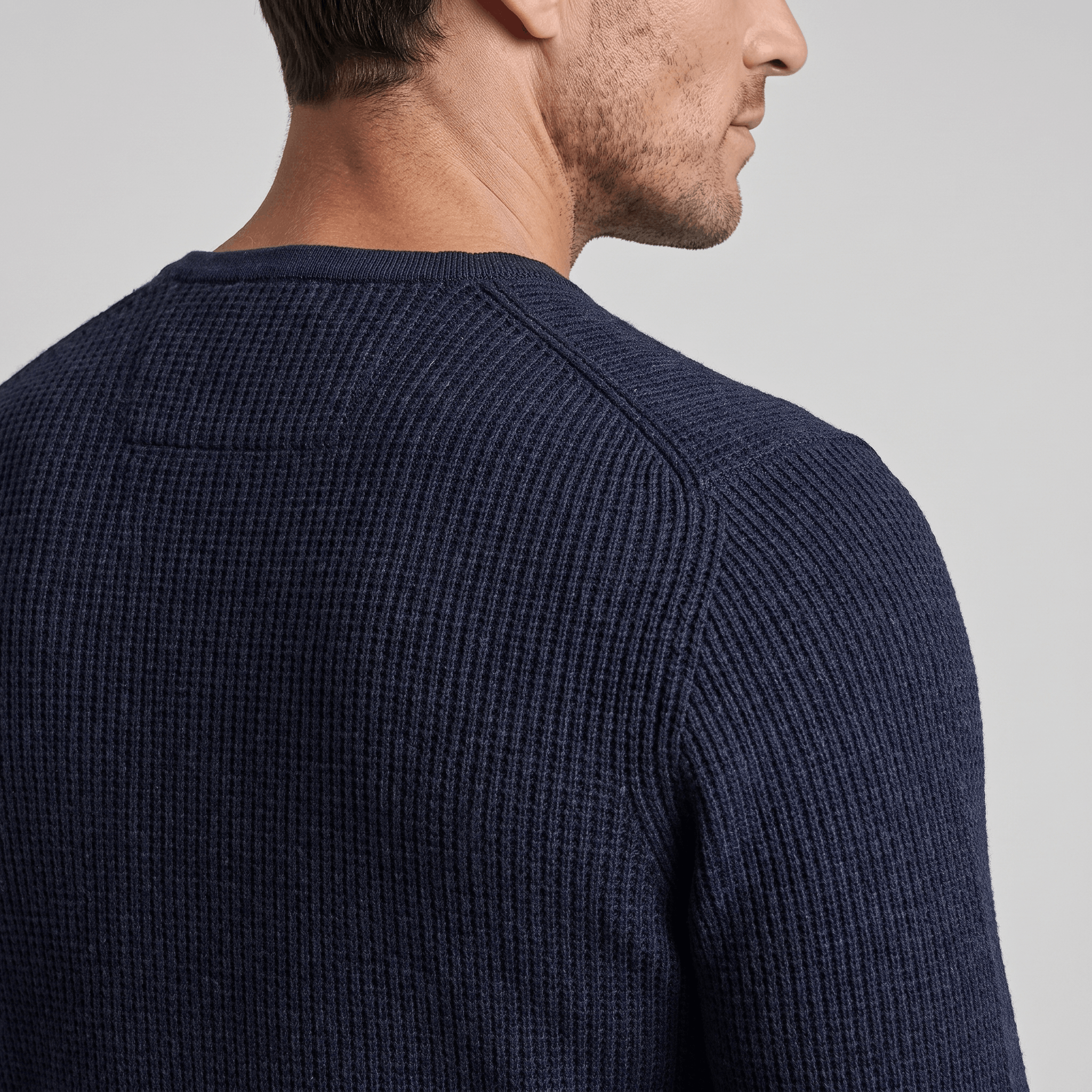 Navy blue ribbed knit henley sweater with a regular fit and structured shoulder detail on a man.