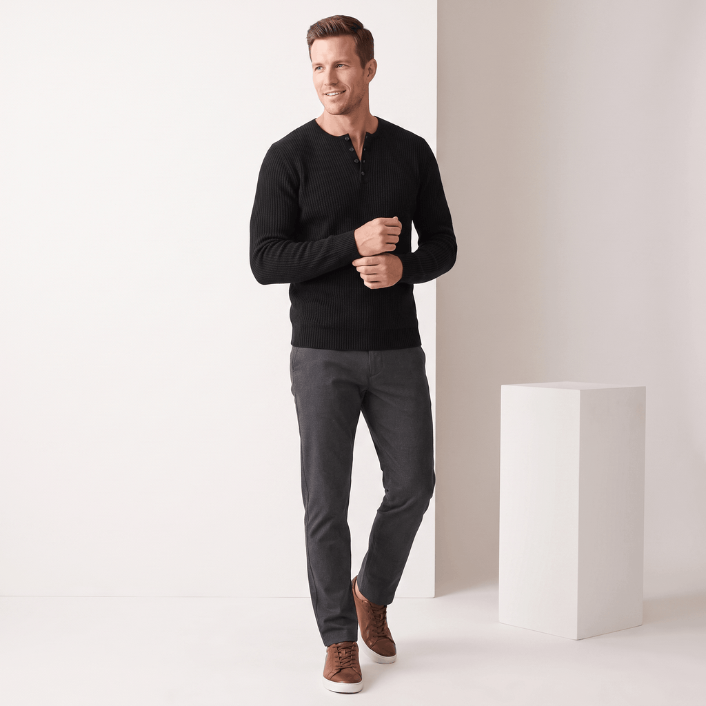 Black ribbed knit henley sweater with a four-button placket, worn in a regular fit with dark trousers and brown sneakers.