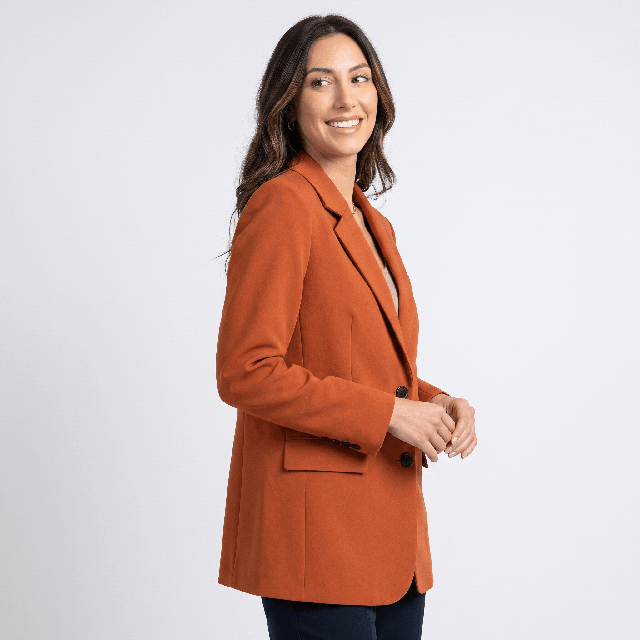Female model wearing a burnt orange tailored blazer with notched lapels and a single-button closure.