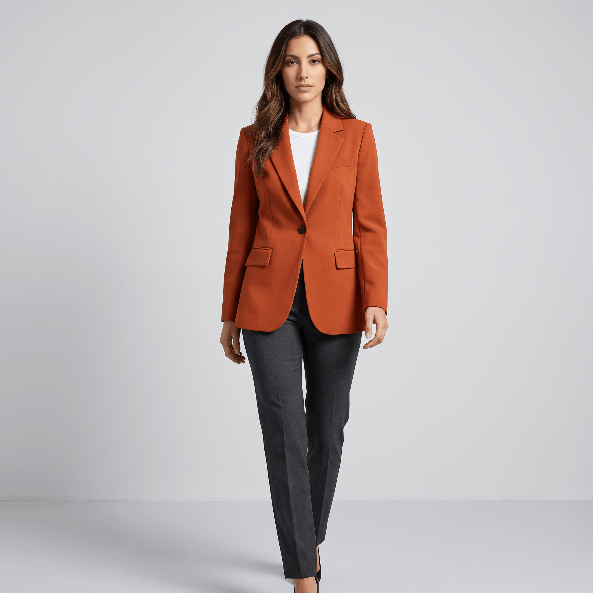 Female model wearing the burnt orange blazer with dark trousers and heels.