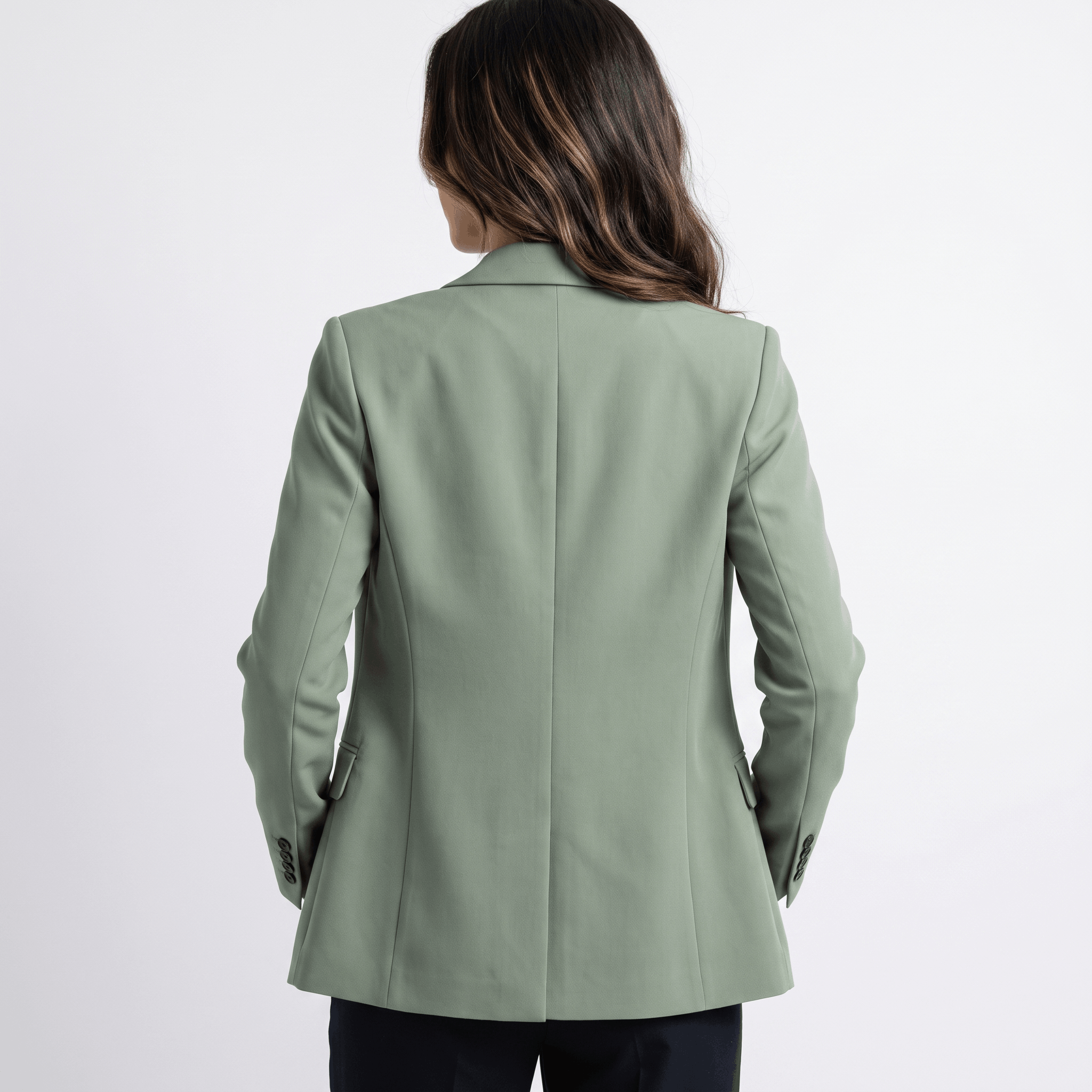 Female model wearing the sage green blazer, highlighting the fitted back and clean tailoring.