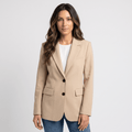 Female model wearing a ivory tailored blazer with a single-button closure, notched lapels, flap pockets, and a white top with blue jeans.