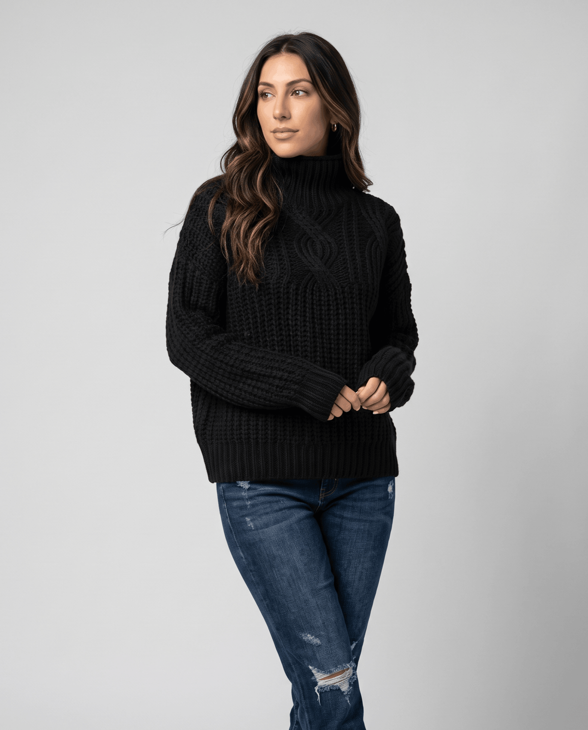 Black Chunky Cable Knit Sweater worn by a female model with blue jeans, featuring a mock neck, relaxed fit, chunky cable knit texture, and long sleeves.