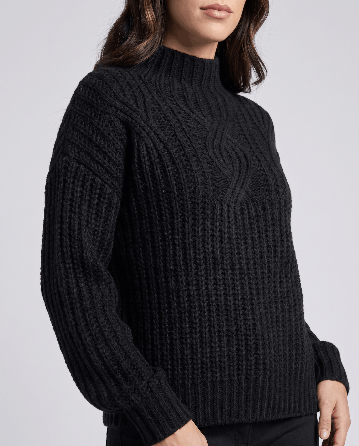 Black Chunky Cable Knit Sweater worn by a female model, shown from the front with a mock neck, relaxed fit, chunky cable knit texture, and long sleeves.