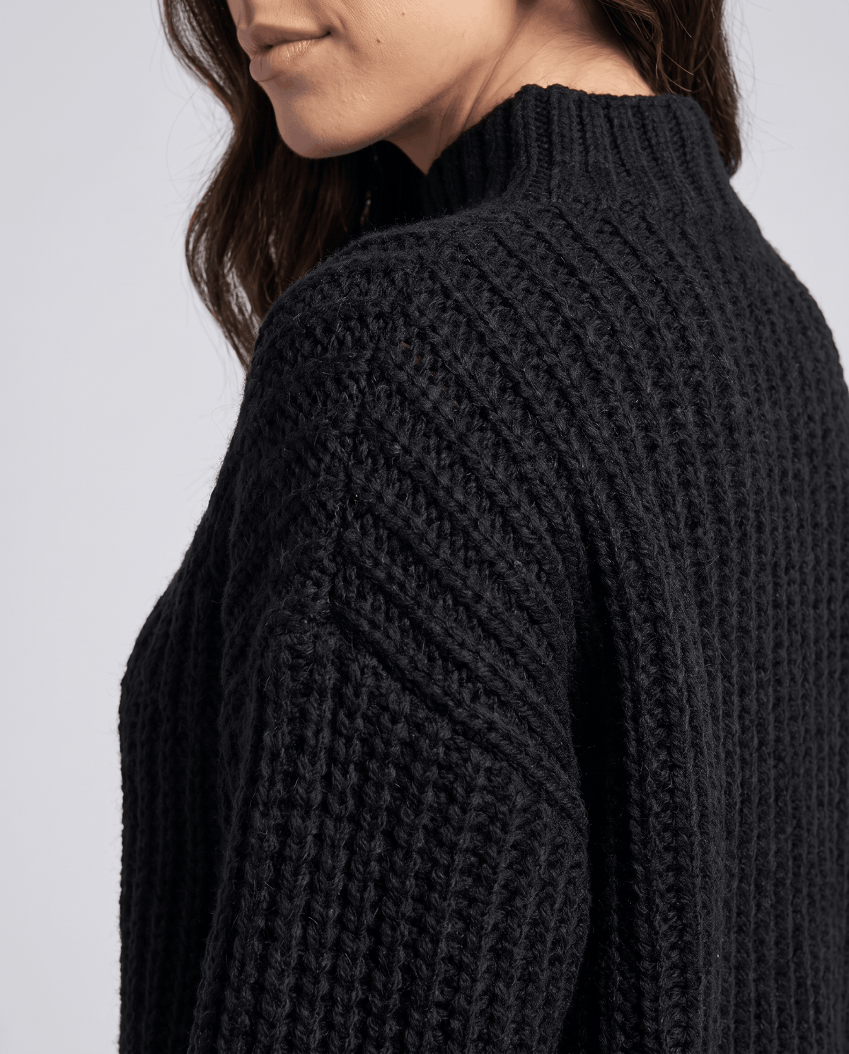 Close-up of the black Chunky Cable Knit Sweater worn by a female model, highlighting the mock neck, chunky cable knit texture, and relaxed fit.