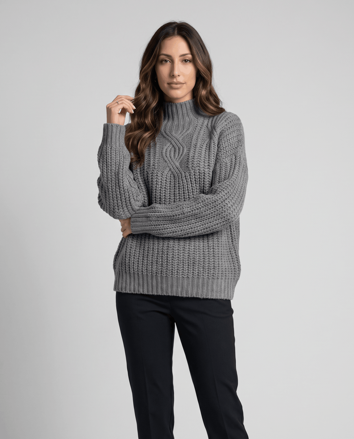 Gray Chunky Cable Knit Sweater worn by a female model with dark pants, featuring a mock neck, relaxed fit, chunky cable knit texture, and long sleeves.
