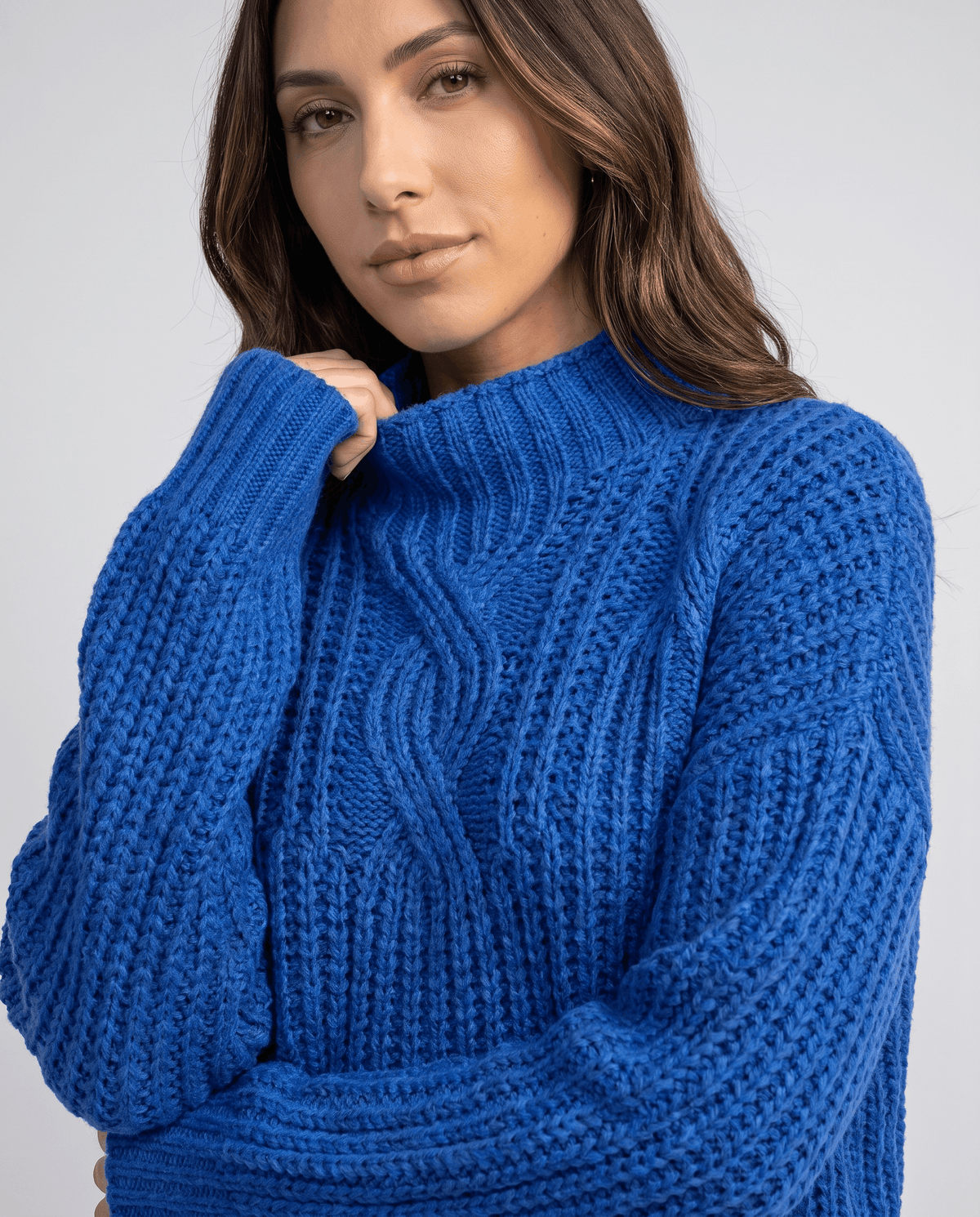 Blue Chunky Cable Knit Sweater worn by a female model, shown in close-up to highlight the mock neck, chunky cable knit texture, and relaxed fit.
