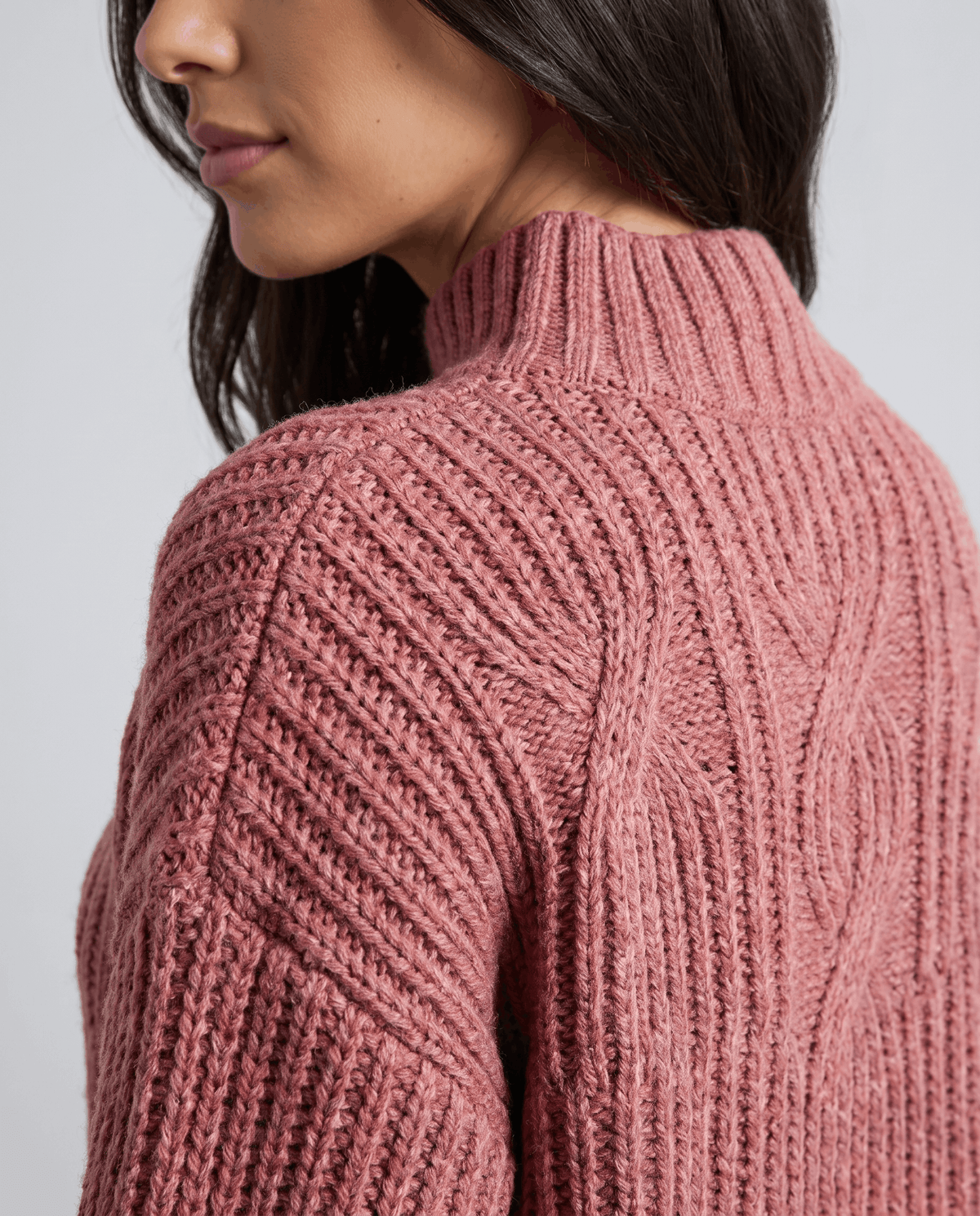 Close-up of the pink Chunky Cable Knit Sweater worn by a female model, showcasing the chunky cable knit texture, mock neck, and relaxed fit.