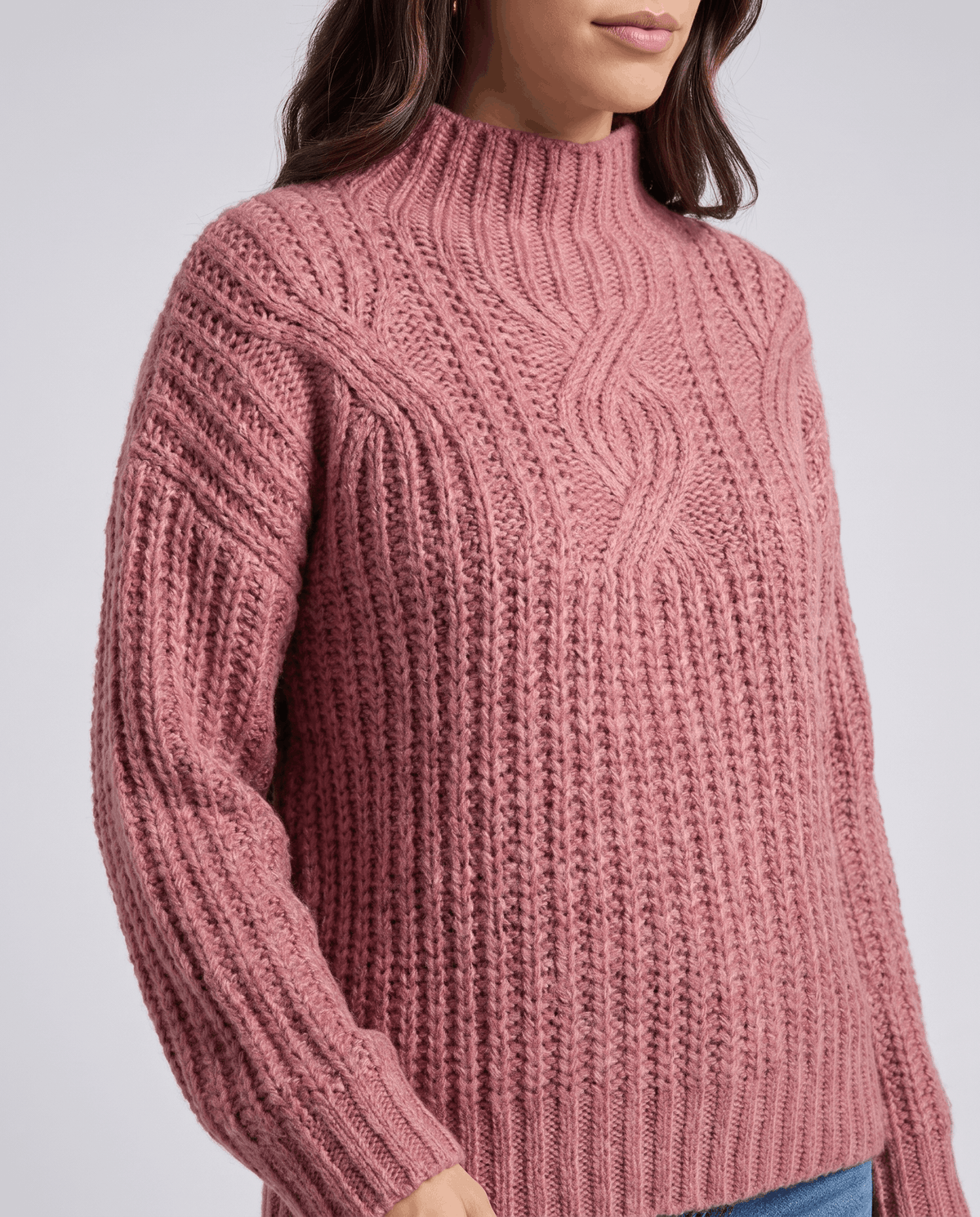 Pink Chunky Cable Knit Sweater worn by a female model, highlighting the relaxed fit, mock neck, textured cable knit pattern, and long sleeves.
