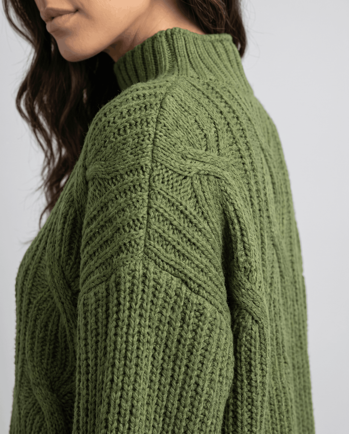 Close-up of the green Chunky Cable Knit Sweater worn by a female model, highlighting the chunky cable knit texture, mock neck, and relaxed fit.