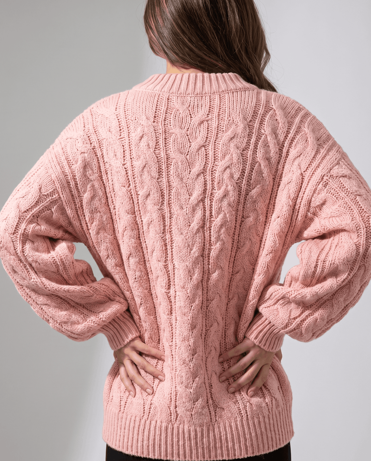 Pink Chunky Cable Knit Sweater worn by a female model from the back, featuring an oversized fit, textured cable knit pattern, long sleeves, and ribbed hem.