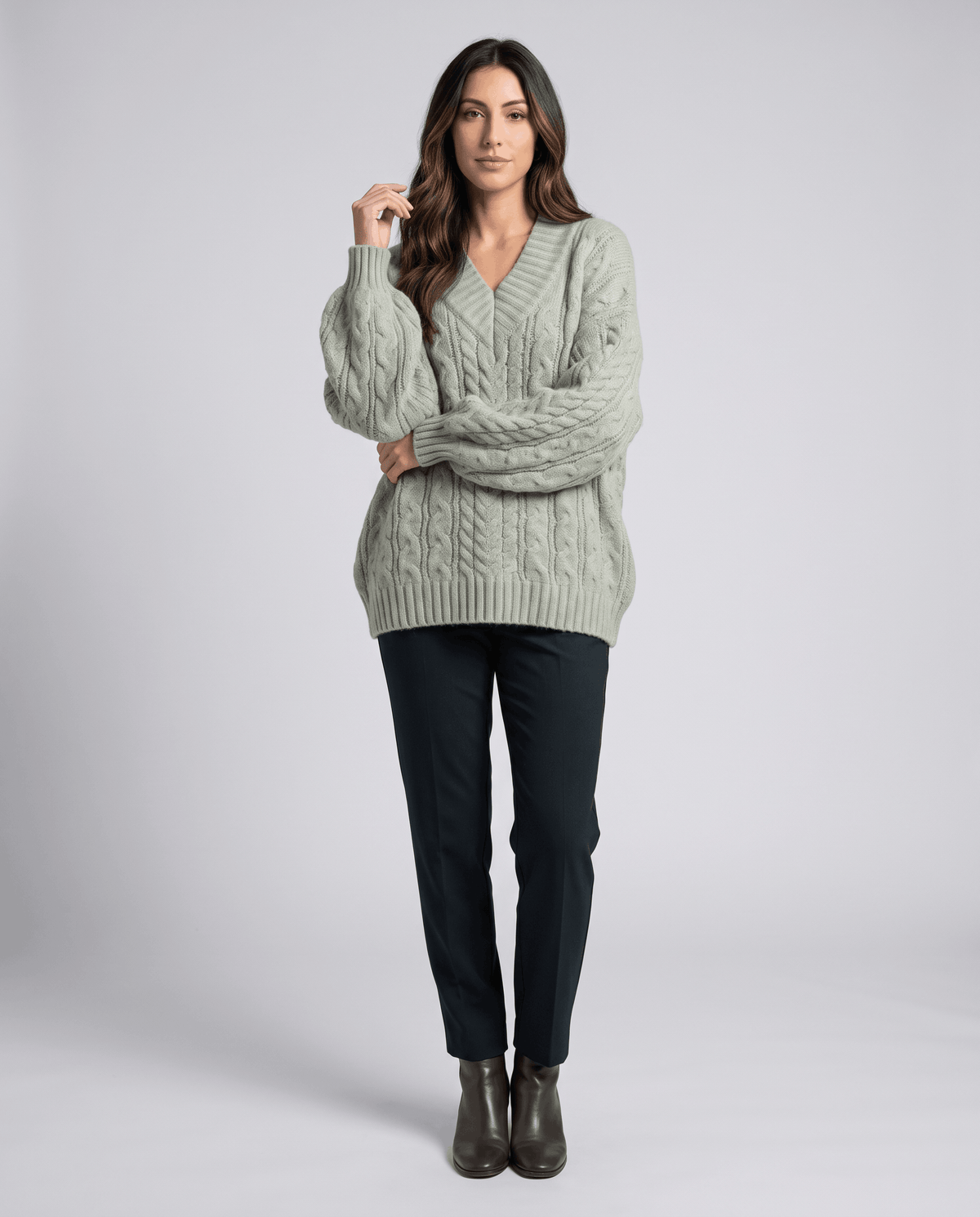 Light green Chunky Cable Knit Sweater worn by a female model with dark pants and boots, featuring an oversized fit, textured cable knit pattern, and long sleeves.