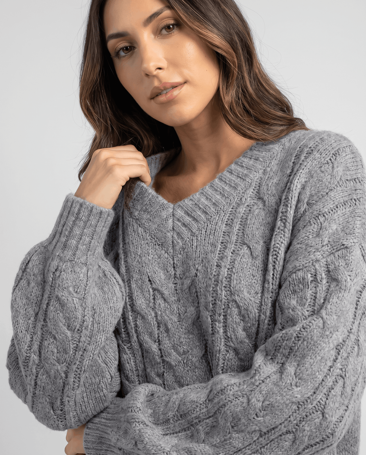 Close-up of the gray Chunky Cable Knit Sweater worn by a female model, highlighting the textured cable knit pattern, V-neckline, oversized fit, and long sleeves.