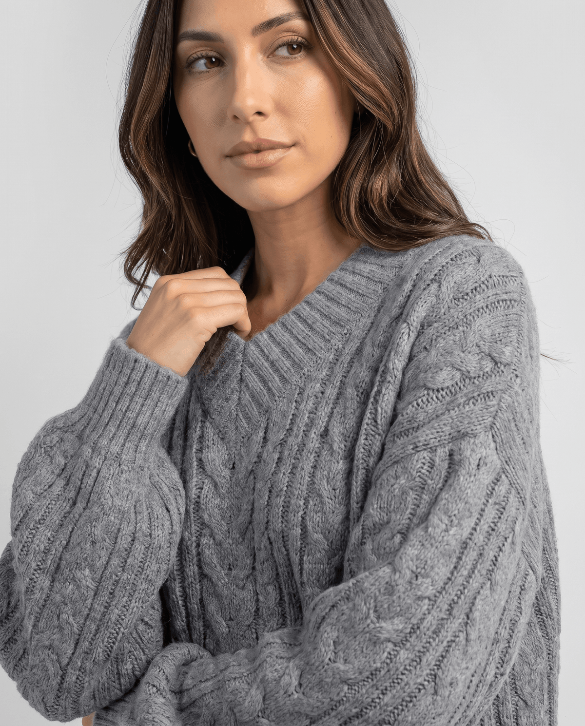Close-up of the gray Chunky Cable Knit Sweater worn by a female model, showcasing the textured cable knit pattern, V-neckline, and relaxed fit.