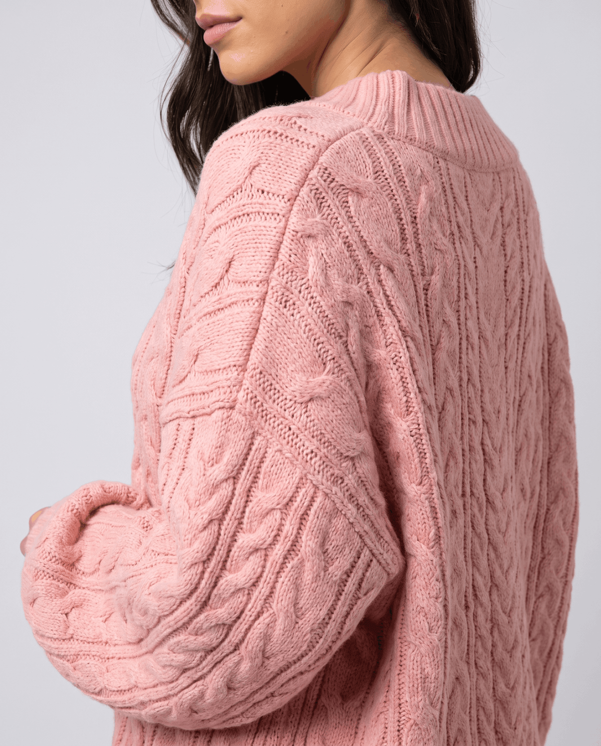 Pink Chunky Cable Knit Sweater worn by a female model from the side, showcasing the textured cable knit pattern, relaxed oversized fit, and long sleeves.