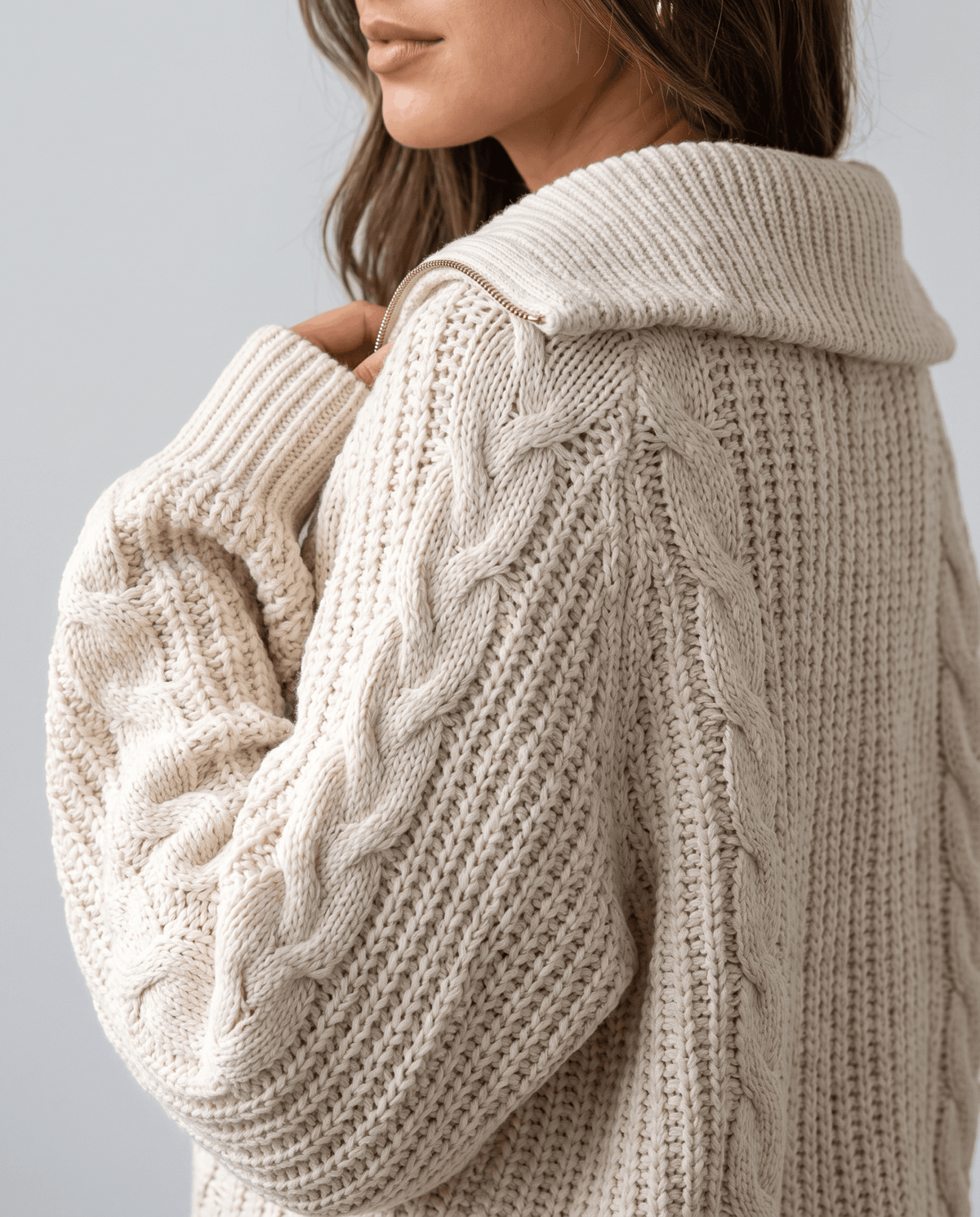 Close-up of the cream Chunky Cable Knit Sweater worn by a female model, highlighting the stand collar, half-zip front, and chunky cable knit texture.