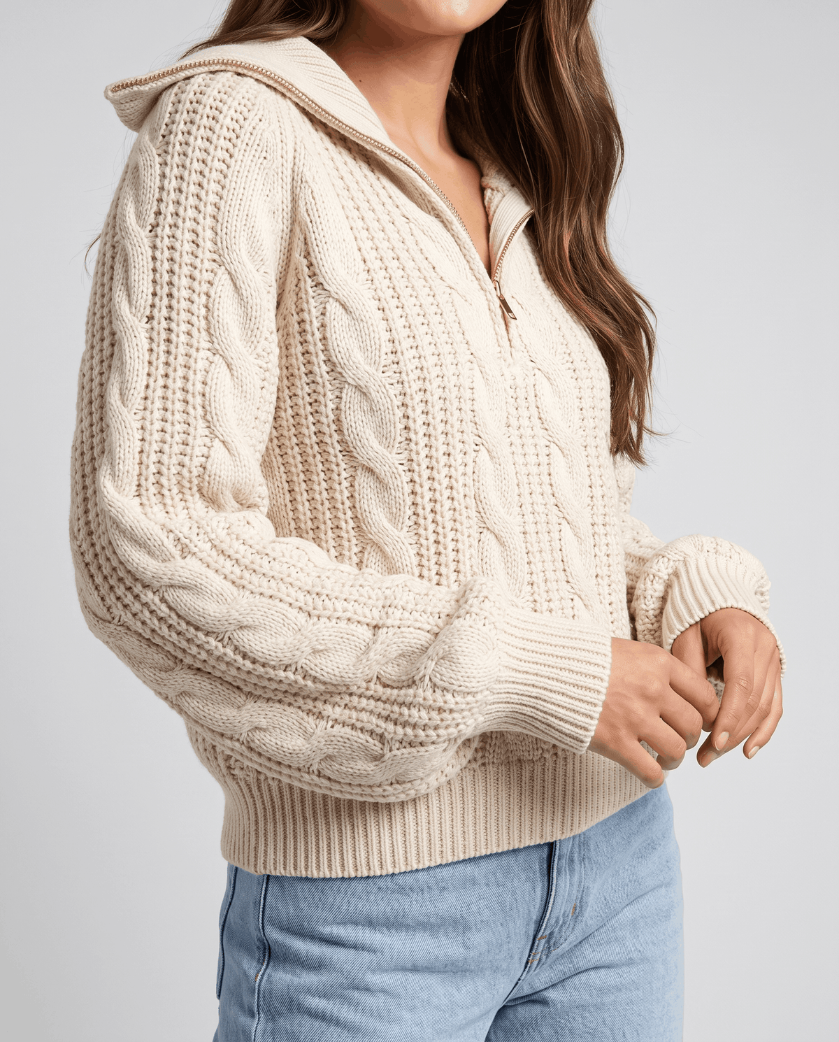 Cream Chunky Cable Knit Sweater worn by a female model from the side, showcasing the stand collar, half-zip closure, textured cable knit pattern, and relaxed fit.