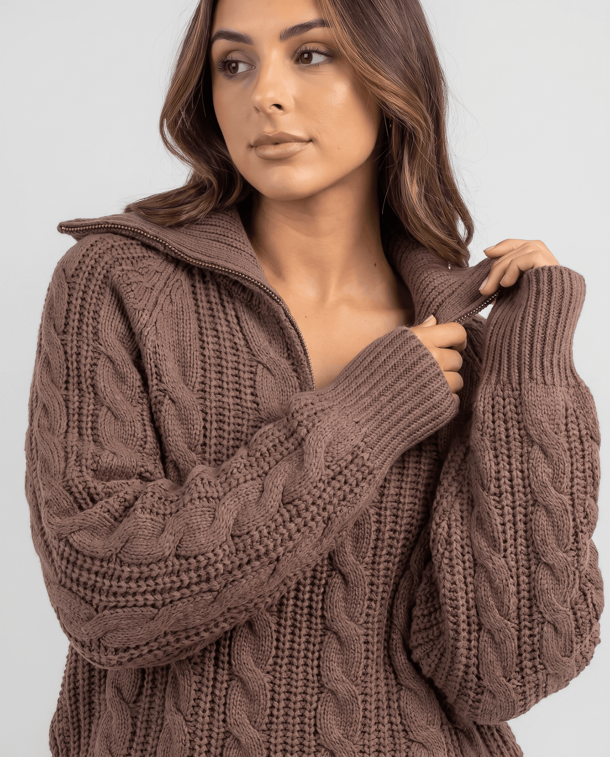 Close-up of the brown Chunky Cable Knit Sweater worn by a female model, highlighting the stand collar, half-zip front, and chunky cable knit texture.