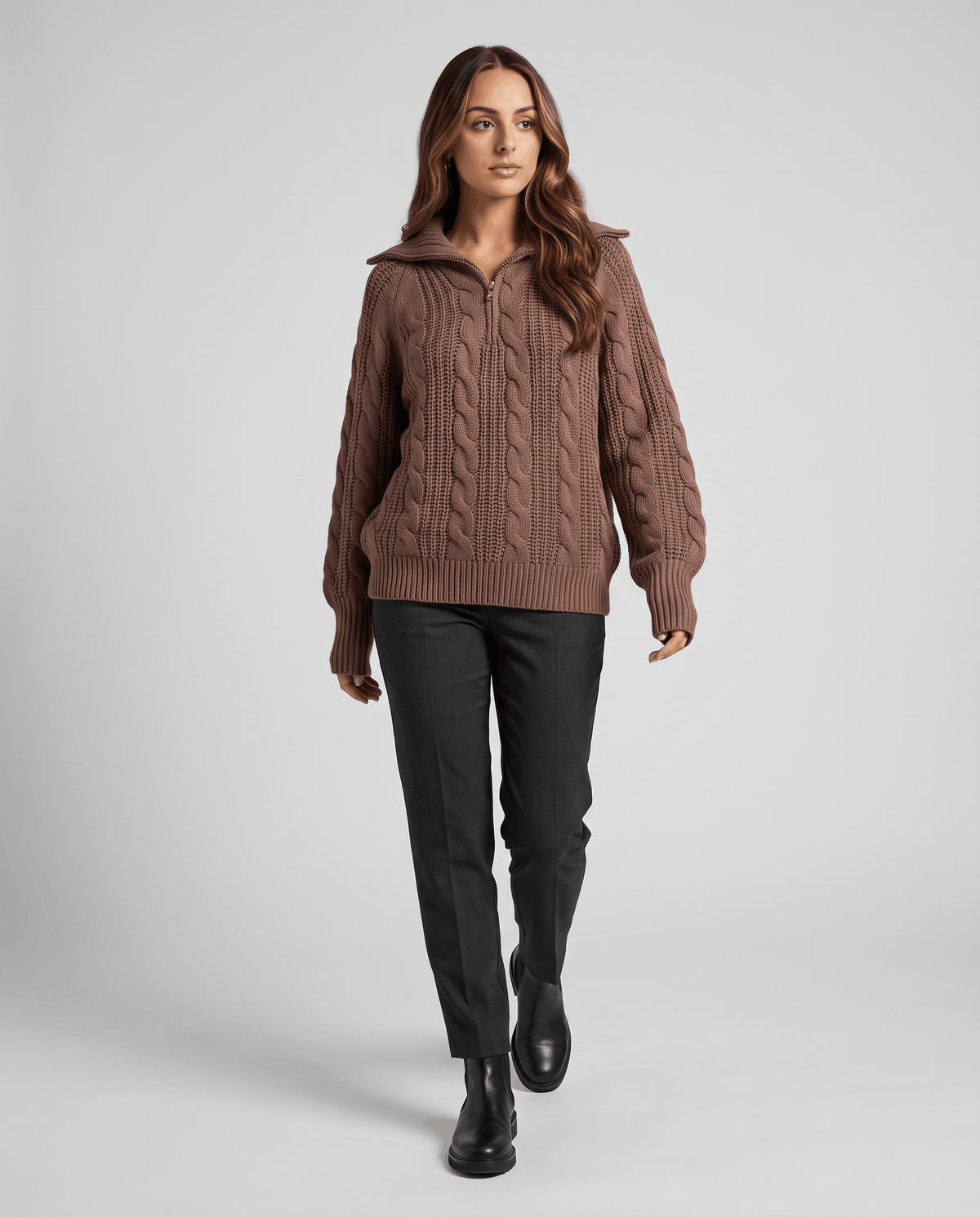 Brown Chunky Cable Knit Sweater worn by a female model with dark pants and boots, featuring a stand collar, half-zip front, chunky cable knit texture, and relaxed fit.