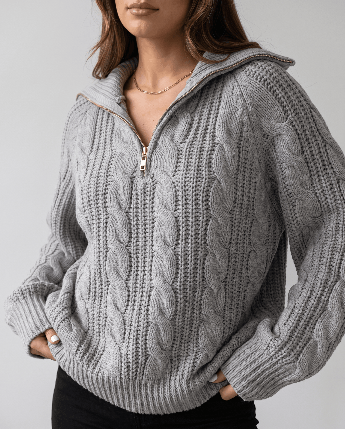 Gray Chunky Cable Knit Sweater worn by a female model, shown from the front with a stand collar, half-zip closure, chunky cable knit texture, and relaxed fit.