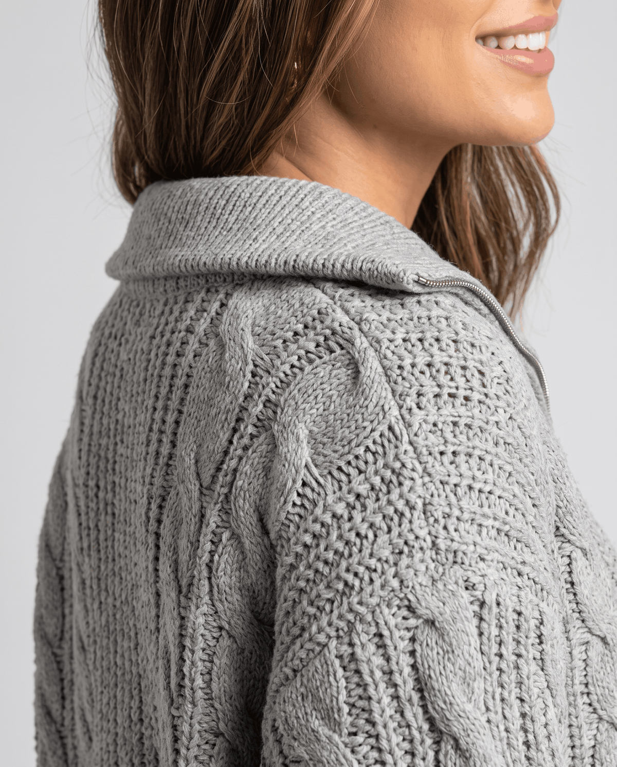 Gray Chunky Cable Knit Sweater worn by a female model from the side, highlighting the stand collar, textured cable knit pattern, half-zip front, and relaxed fit.