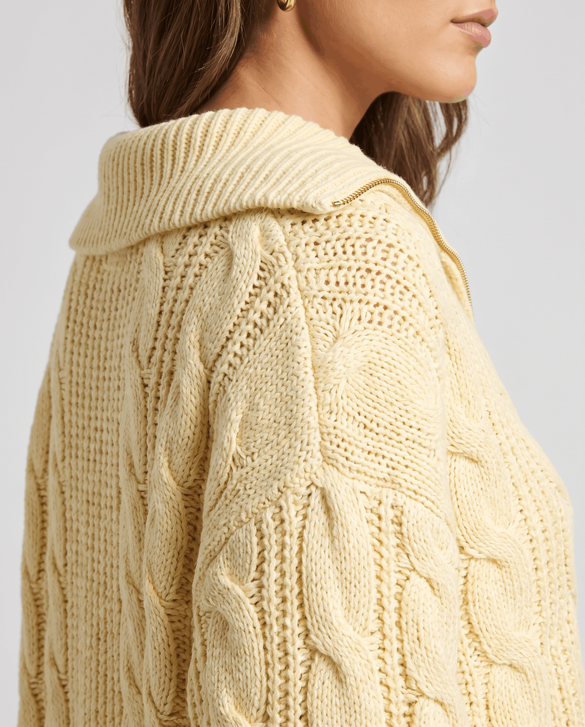 Close-up of the yellow Chunky Cable Knit Sweater worn by a female model, highlighting the stand collar, textured cable knit pattern, and half-zip front.