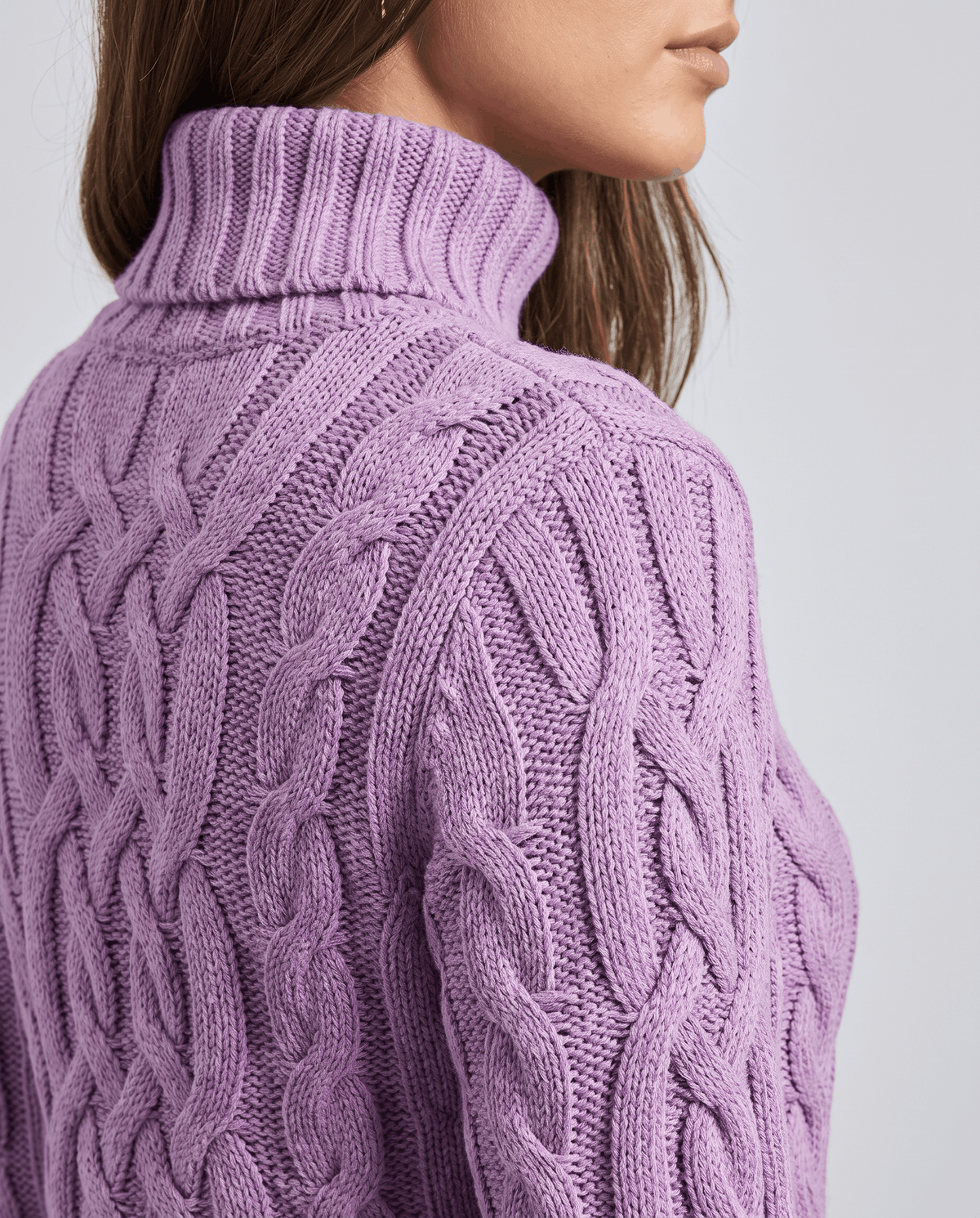 Purple Chunky Cable Knit Sweater worn by a female model, shown from the back with a turtleneck, textured cable knit pattern, long sleeves, and ribbed trim.