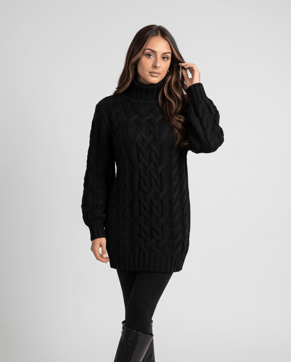 Black Chunky Cable Knit Sweater worn by a female model with black leggings, featuring a turtleneck, textured cable knit pattern, long sleeves, and ribbed trim.