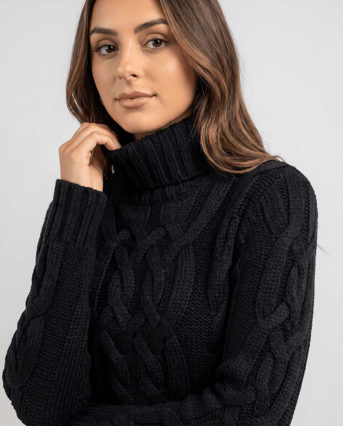 Close-up of the black Chunky Cable Knit Sweater worn by a female model, showcasing the turtleneck collar, chunky cable knit texture, and ribbed trim.