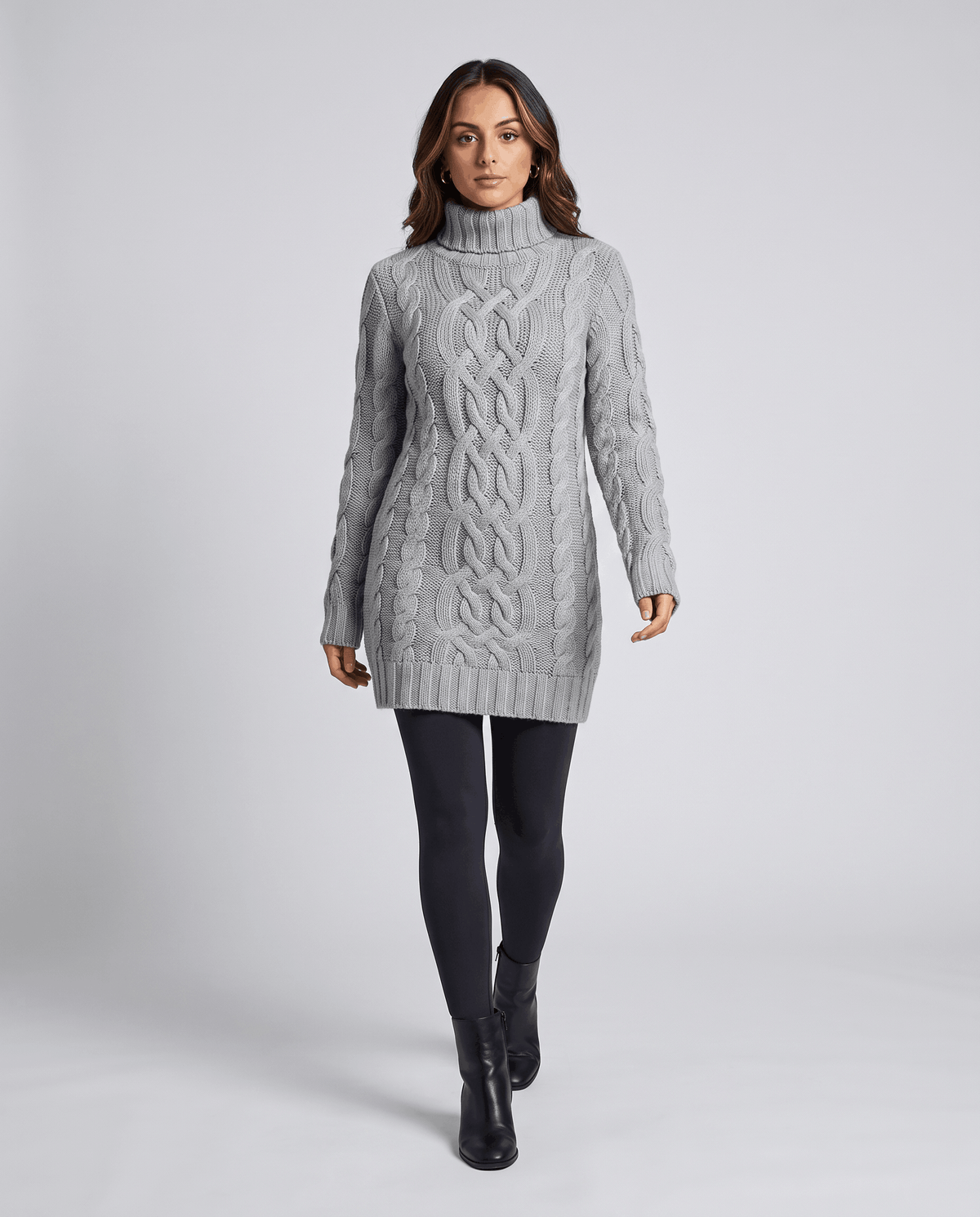 Gray Chunky Cable Knit Sweater worn by a female model with black leggings, featuring a turtleneck, textured cable knit pattern, long sleeves, and ribbed trim.