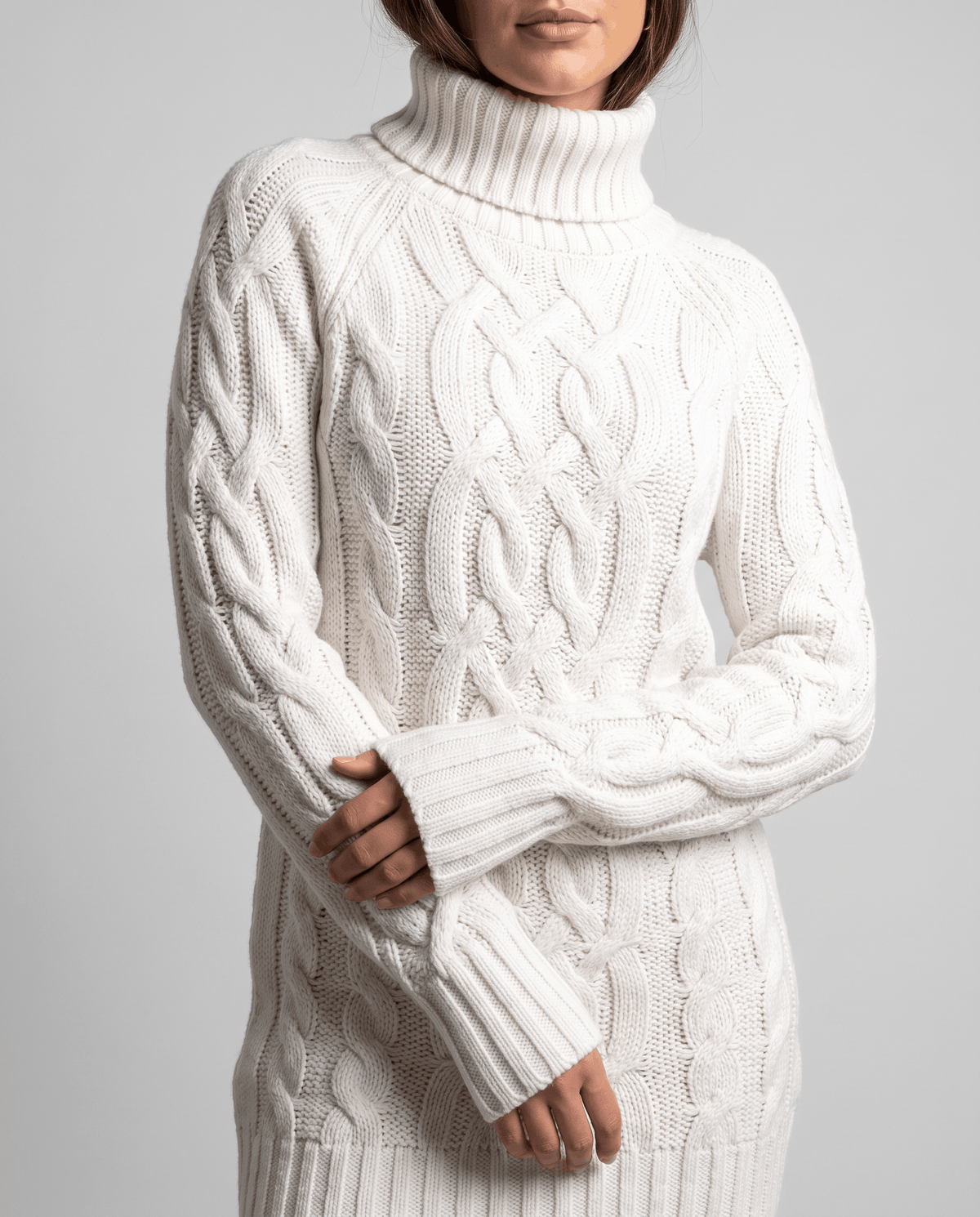 White Chunky Cable Knit Sweater worn by a female model, shown in close-up with a turtleneck, chunky cable knit texture, long sleeves, and ribbed trim.