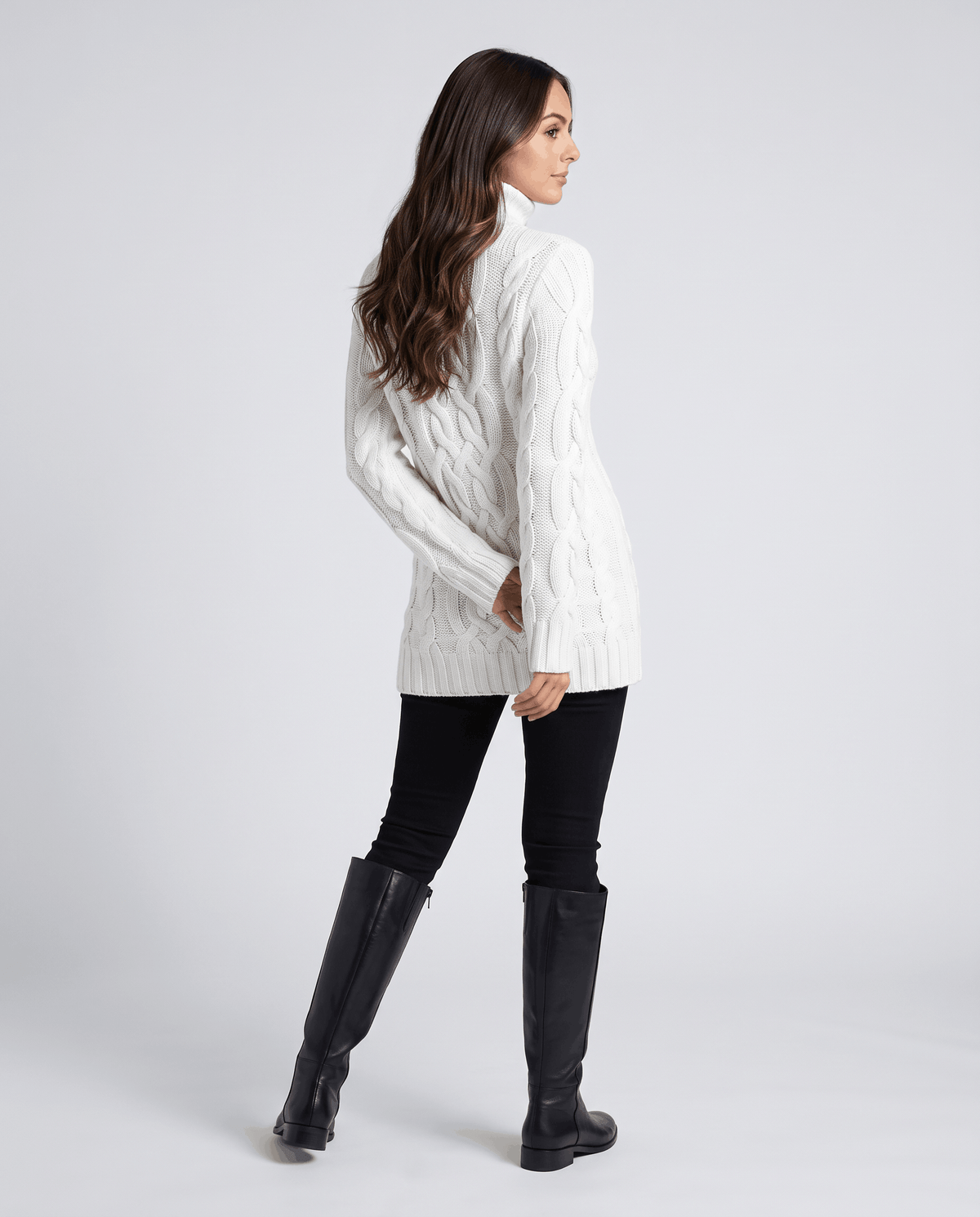 White Chunky Cable Knit Sweater worn by a female model from the side, featuring a turtleneck, textured cable knit pattern, long sleeves, and ribbed trim.