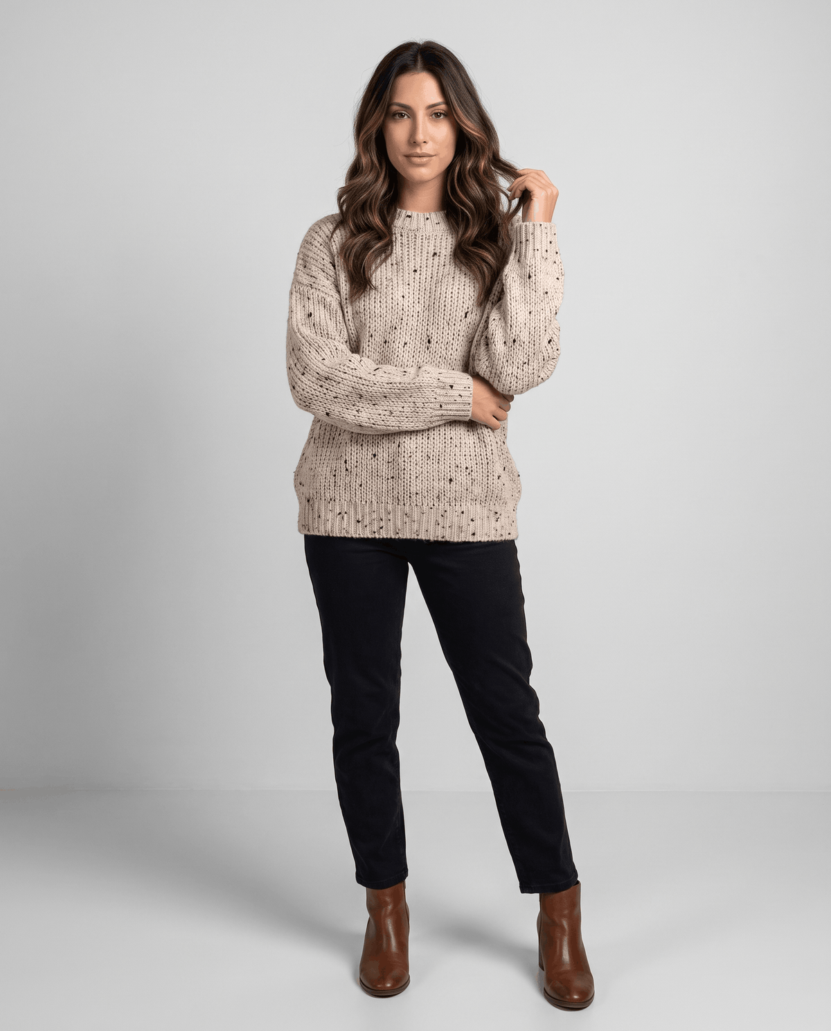 Beige Chunky Knit Sweater worn by a female model with black leggings and boots, featuring an oversized fit, textured knit pattern, and long balloon sleeves.