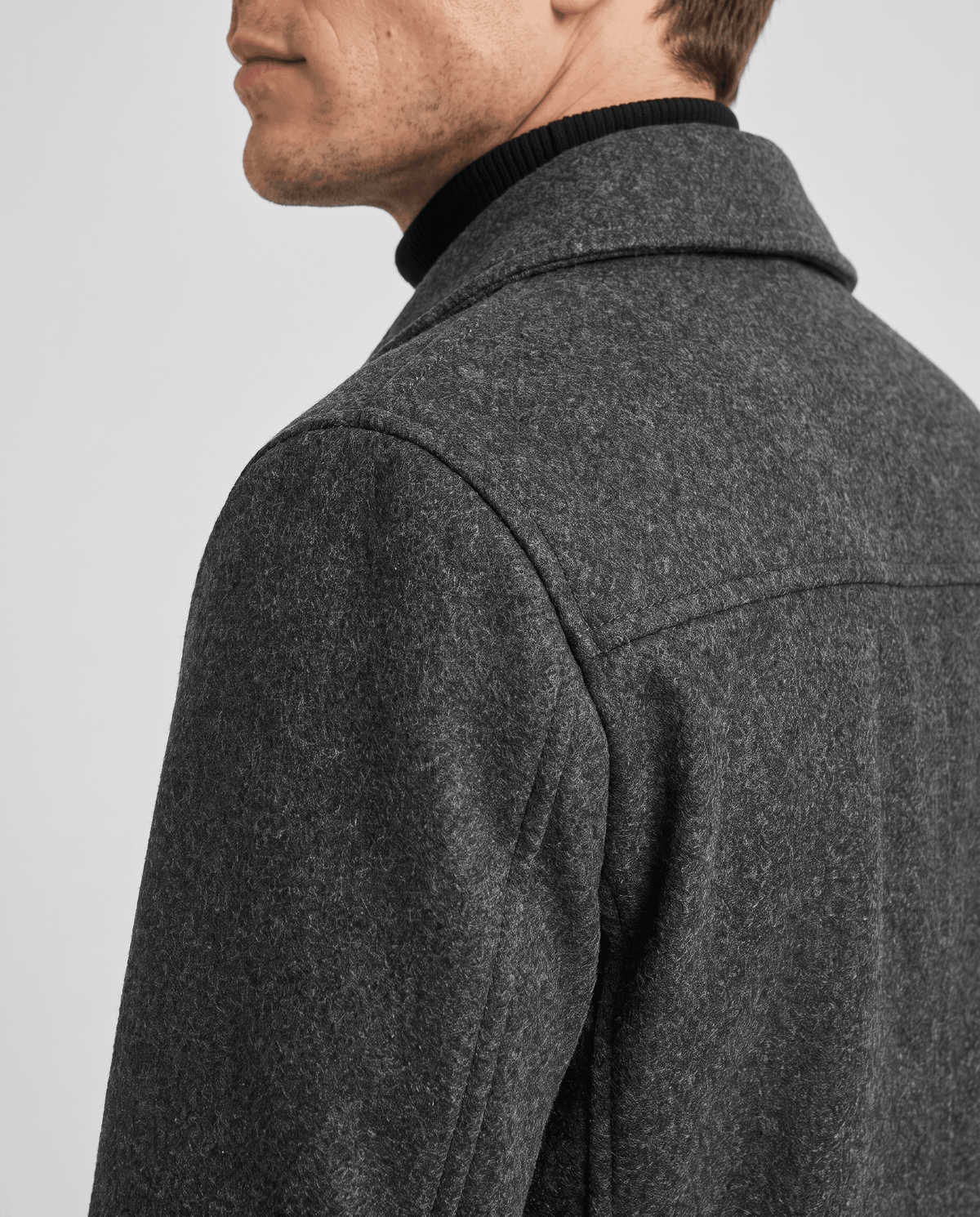 Close-up of a gray classic double-breasted trench coat, showing the structured collar and tailored shoulder detail